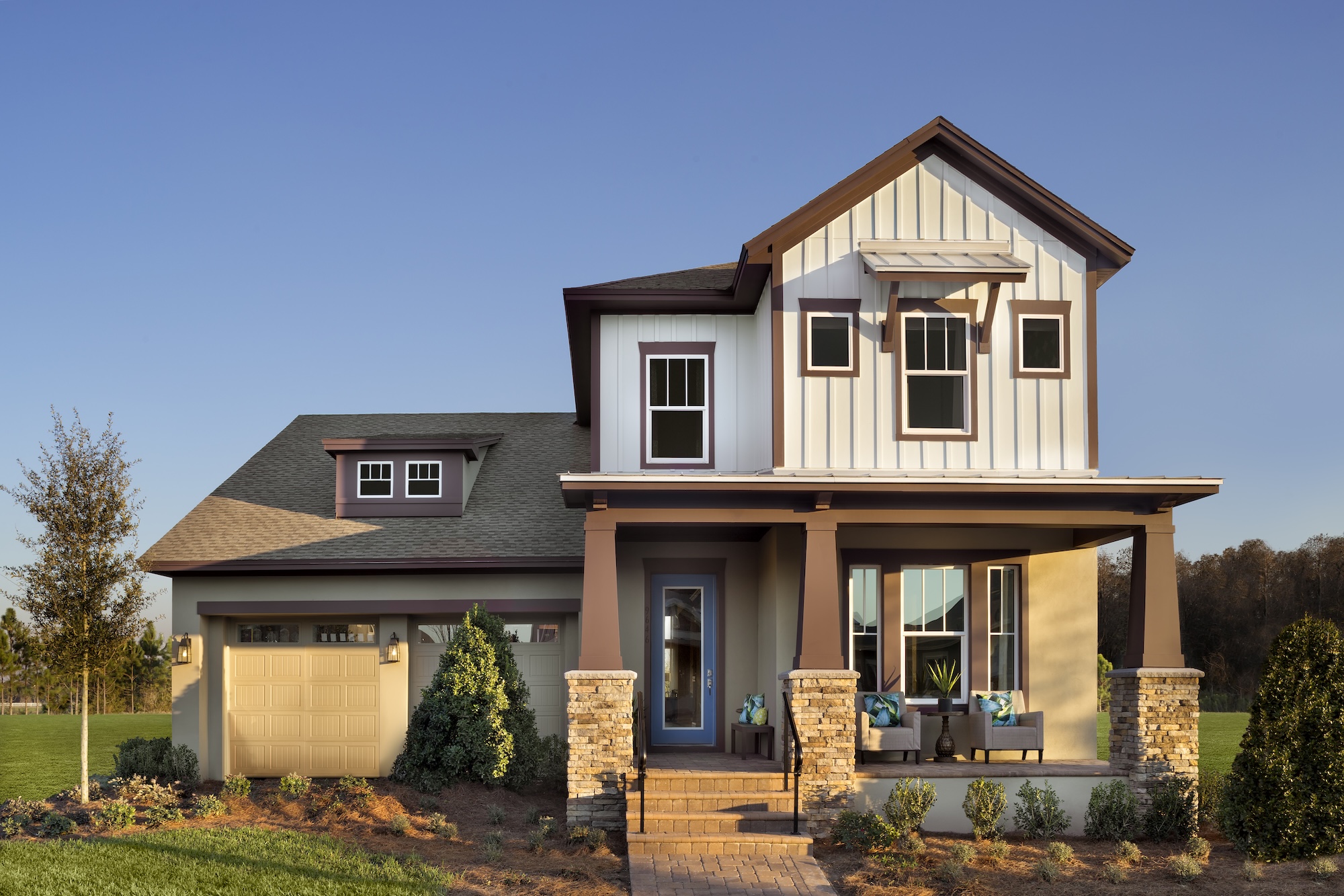 Image of the David Weekley Manville model home in Laureate Park in Lake Nona Orlando, FLorida. The home is tan on the first floor and off-white on the second floor with a two car garage.